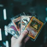 A hand holds collectible Charizard Pokemon cards with a blurred bokeh background. Perfect for trading card enthusiasts.