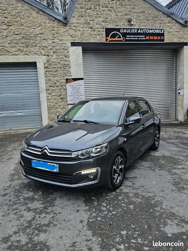 Gray Citroën sedan parked in front of a stone garage building with a closed metal shutter and a GauLier Automobile sign above the door.